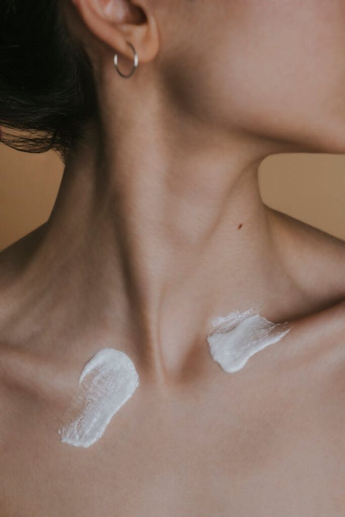 Detailed image showing a woman's neck with skincare cream applied in a studio setting.